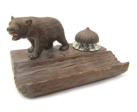 A 20thC Black Forest desk stand, surmounted by a carved bear, beside glass ink well with carved stopper and recess for pens, 