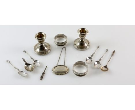 Selection of silver items to include a pair of dwarf candlesticks, two napkin rings, decanter label and six Apostle teaspoons