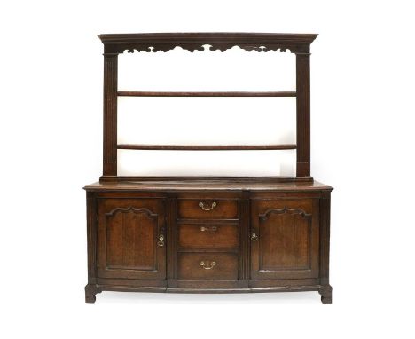 A Mid 18th Century Oak Enclosed Dresser and Rack, the upper section with a wavy shaped apron above three fixed shelves and fl