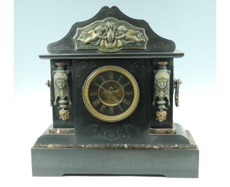 A monumental black slate mantle clock, having a drum movement striking on a gong, the case having freestanding gilt metal col