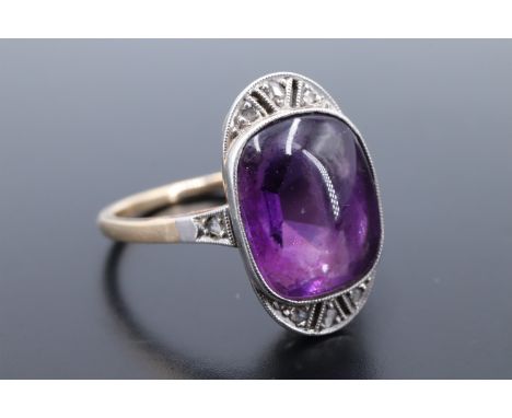 A 1930s Art Deco amethyst cabochon dress ring, the cushion shaped stone of approx 10 mm x 8 mm bezel-set on an elliptical fie