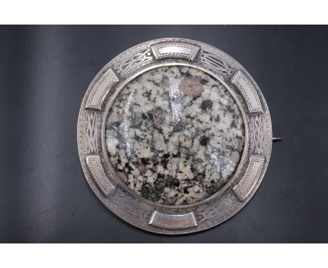 A large late 19th / early 20th Century Scottish white metal mounted polished granite cabochon boss brooch, the mounted engrav
