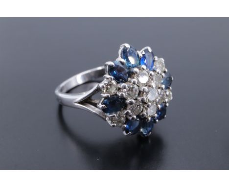 A cluster set diamond and sapphire ring, being three terraces of stones, a central 3 mm brilliant diamond surrounded by six f