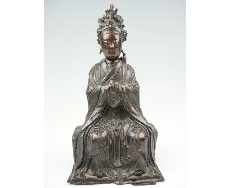 A 19th Century cast bronze figure of Guanyin, posed sitting with hands clasped and looking ahead, the base having a period re