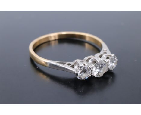 A vintage three-stone diamond ring, the stones of approx 0.6 ct aggregate weight platinum claw set on an 18 ct gold shank, O/