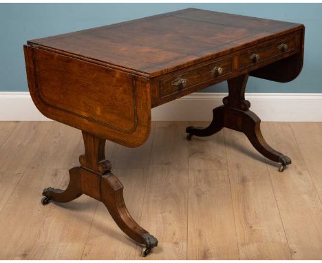 A Regency rosewood sofa table with brass strung decoration, all on shaped end supports with splayed legs and hairy paw feet a