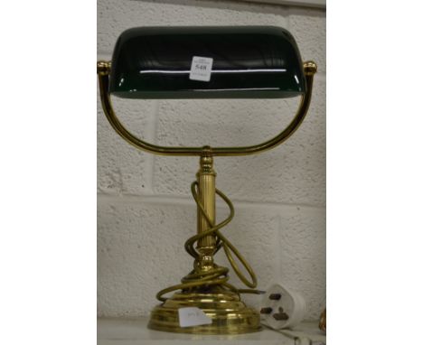 A brass desk lamp with a green glass shade.