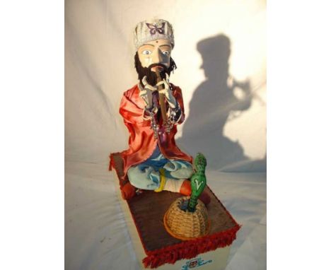 Red snake charmer Automaton made out of bisque, wood and fabric. Sitting cross-legged and playing the flute while the snake r