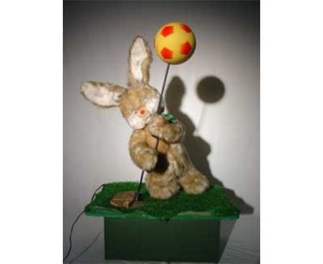 Rabbit and Balloon Plush automaton with composition and synthetic fur. Standing and operating a crank at the end of which is 