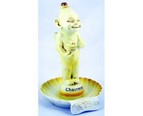 CHAIRMAN MATCHSTRIKER/ ASHTRAY FIGURE. 10.5ins tall, yellow glazed imp like figure stood on shell base, matcholder behind its