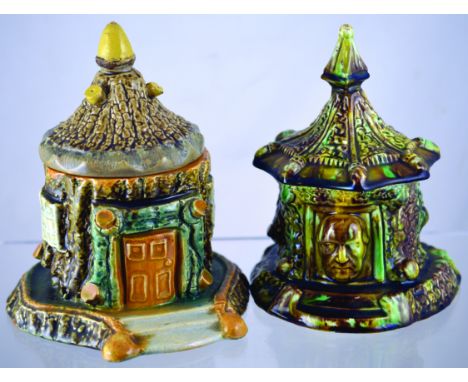 PAIR OF ENGLISH CERAMIC TOBACCO JARS. Rustic style jars, one formed as a cottage, one with face mask in relief in green & bro