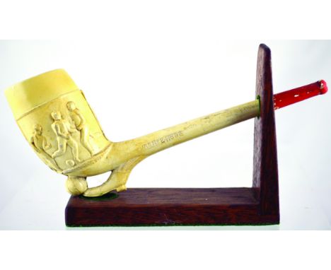 LARGE CLAY PIPE. 8.5ins long on wooden stand, footballers pipe, boot kicking ball to base of pipe, footballers to pipe bowl. 