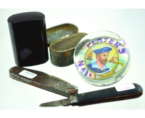 MIXED GROUP. Bakelite snuff box, tin Victorian nutmeg grater, 2 penknives & Players Navy Cut glass paperweight. (5) NR