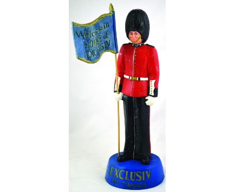 EXCLUSIV TOBACCOS. 21ins tall, guardsman soldier figure in red & black holding flag WELCOME IN HOUSE OF EXCLUSIV stood on blu
