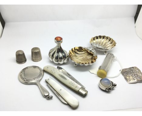 A collection of silver oddments silver shell shaped salts thimbles a miniature mirror mother of Pearl and silver folding knif