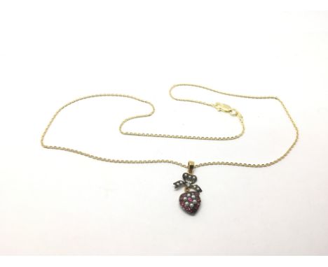 A yellow metal heart shaped pendant set with ruby, pearl and a small diamond.