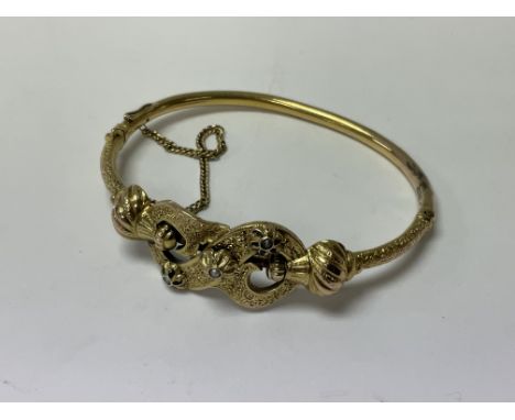 A Victorian yellow metal bangle with engraved decoration inset with seed pearls and blue enamel.