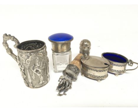 An Indian white metal cup a silver and blue enamel scent bottle a silver condiment set and a bottle stopper.