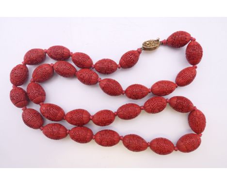 An early 20th century Chinese cinnabar necklace with silver gilt clasp. 62 cm long.