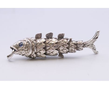 An articulated silver fish with sapphire eyes. 6 cm long. 14.8 grammes total weight.