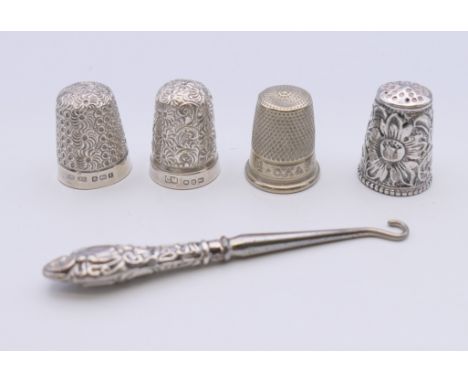 Four silver thimbles and a silver handled button hook.