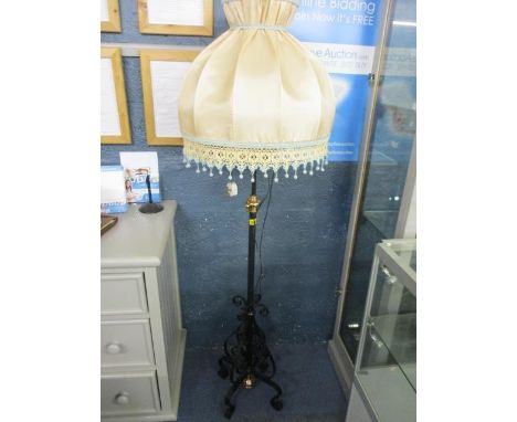 A mid 20th century wrought iron standard lamp with a peach coloured shade 