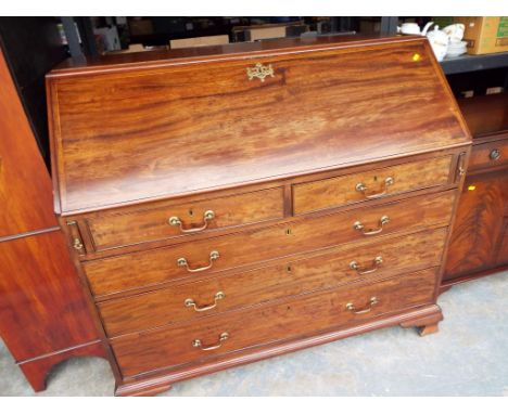A Georgian mahogany bureau, the slope front opening to rest on lopers revealing a pigeon-hole fitted interior with secret com