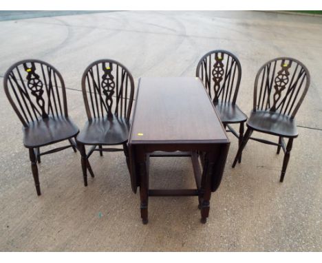 An oak drop left gate leg dining table approx 75cm x 90cm x 147cm and a set of four oak wheel back dining chairs