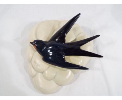 Clarice Cliff - a wall pocket moulded in the style of a cloud decorated in high relief with a swallow in flight # 874, 19.5 c