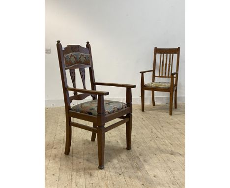 A matched pair of Arts and Crafts period oak carver chairs, each with drop in seat pads upholstered in Morris style fabric, H