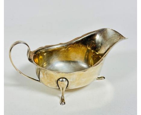 An Edinburgh 1934 silver sauce boat with scalloped border and C scroll handle to sides, raised on three pad feet, (h: 5cm x 1