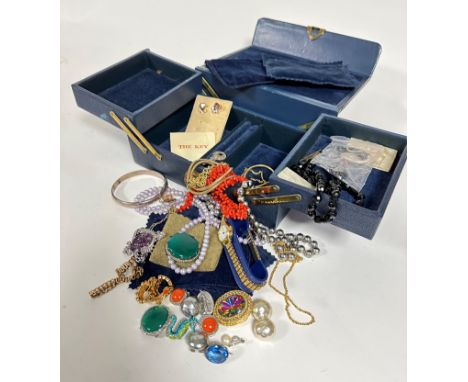 A blue leather vintage jewellery case with fold out concertina sections containing pink coral thong style necklace, a modern 