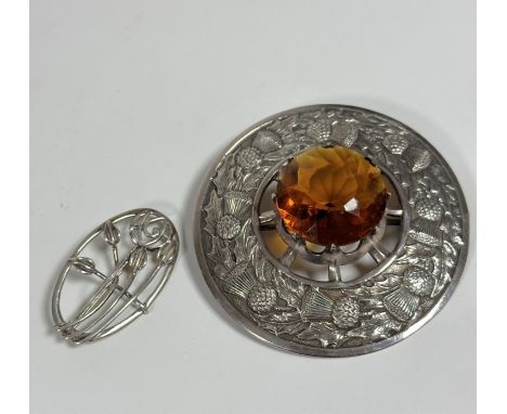 A 19thc style white metal plaid brooch set faceted glass, amber coloured circular panel, mounted in chased thistle and leaf b