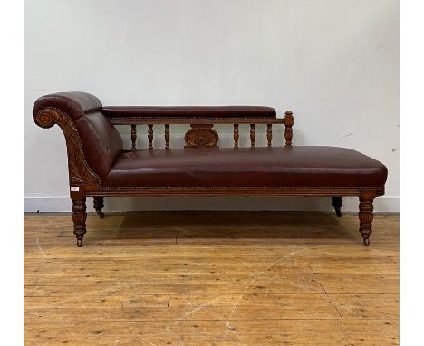 A late Victorian oak framed chaise longue, the arm seat and back rest upholstered in studded faux oxblood leather, the chanel