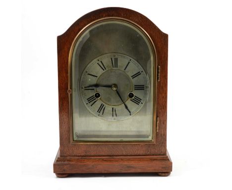 Oak cased mantel clock, eight-day movement striking on a gong, arched silvered dial and chapter ring, with pendulum, 28.5cm.