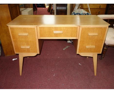 A mid 20th century light oak desk, with five drawers, raised on splayed tapered legs, H.75 W.110 D.47cm 