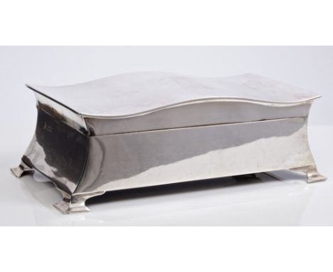 Late 1920s silver cigarette box of rectangular form, with hinged shaped cover and engraved inscription, on four bracket feet 