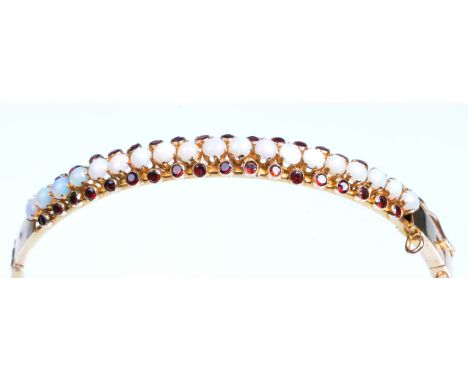 An opal and garnet set hinged bangle
The central row of round cabochon opals with a border of round cut garnets above and bel