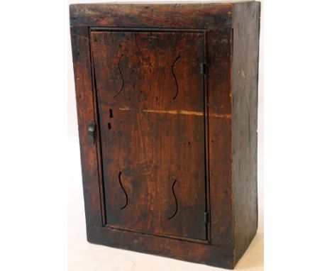 A 18th Century rustic oak handing spice cupboard
The plain rectangular form having a single door with pierced S shaped air ve