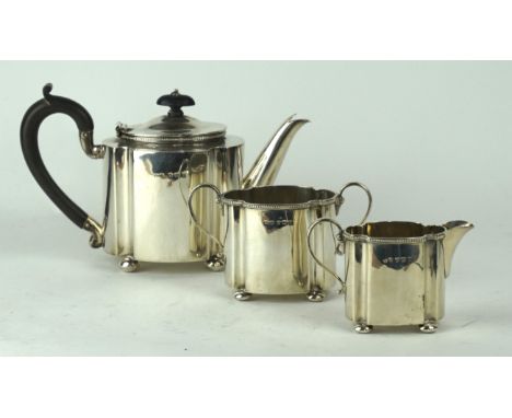 A George V hallmarked silver three piece tea service
Of shaped oval form, having quatreform decoration with cast beaded rims,