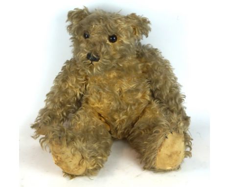 A large gold plush teddy bear
With long curly coat, glass button eyes, black stitched nose and mouth and articulated limbs, h