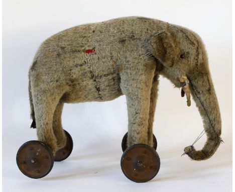 A grey plush elephant 
With glass button eyes and four metal wheels, height 29cm.