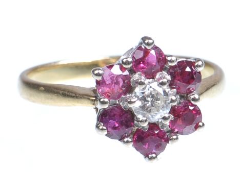 A ruby and diamond set cluster ring
The central round brilliant cut diamond claw set to a border of six round cut rubies, the