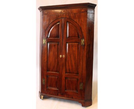 An elegant George III marquetry inlaid mahogany freestanding corner cupboard
The moulded cornice above three inlaid conch she
