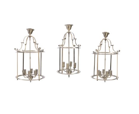 A SET OF THREE MODERN BRASS FRAMED HALL LANTERNS, each with domed cup and arched supports enclosing a six-light centre socket