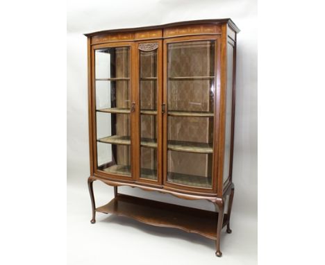 AN EDWARDIAN MAHOGANY DISPLAY CABINET, having a floral swag and ribbon bow marquetry inlaid frieze over double bow front, bev