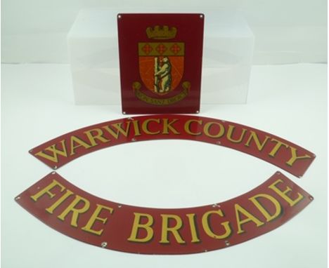 A THREE SECTION NAME PLATE FROM A FIRE ENGINE comprising two red ground crescents inscribed in gold and black text 'Warwick C