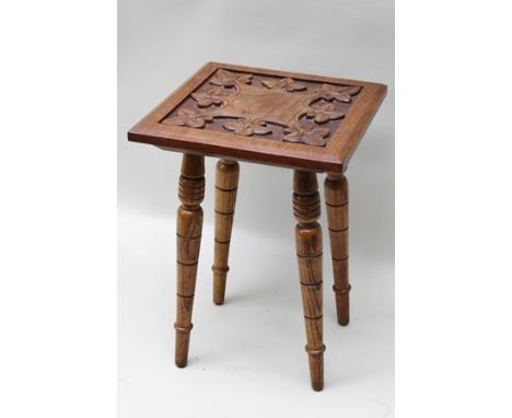 A 20TH CENTURY ARTS & CRAFTS CARVED WOODEN STAND, having bevelled square top on four ring turned splayed legs, 44cm high x 31