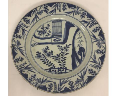 A vintage Chinese blue and white hand painted ceramic plate.  With bamboo decoration to rim and aged staple repair to reverse