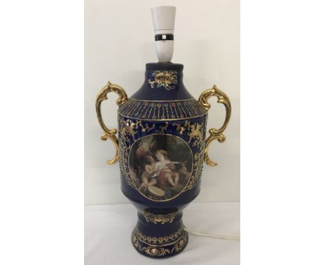 A blue ceramic 2 handled vase/urn, heavily gilded with classical panel design to front and back.  Converted to a table lamp. 